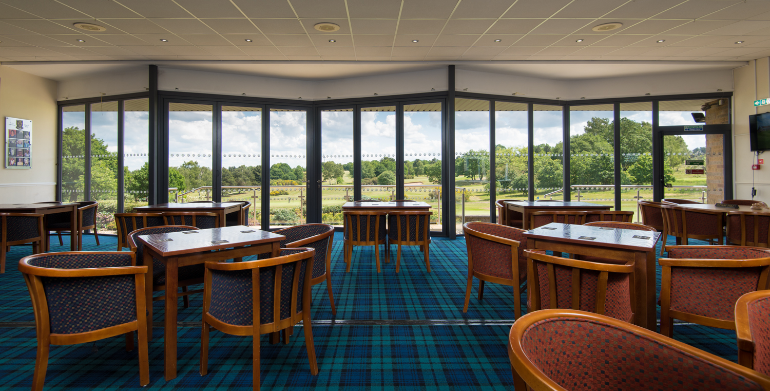 Inside a golf club with chairs and tables looking out onto the course through closed Origin bifold doors