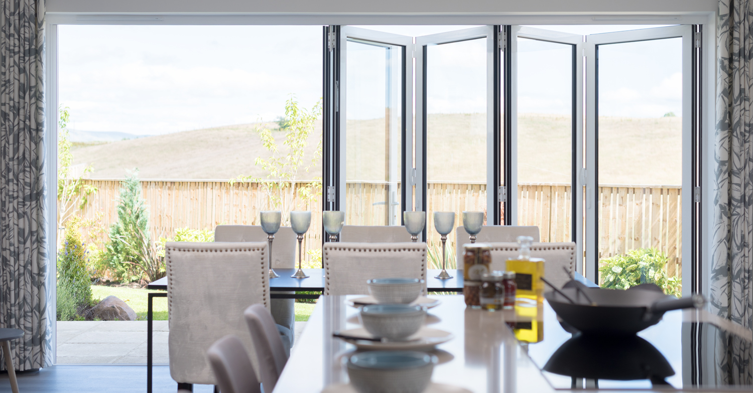 View of a set dining table with half open bifold doors