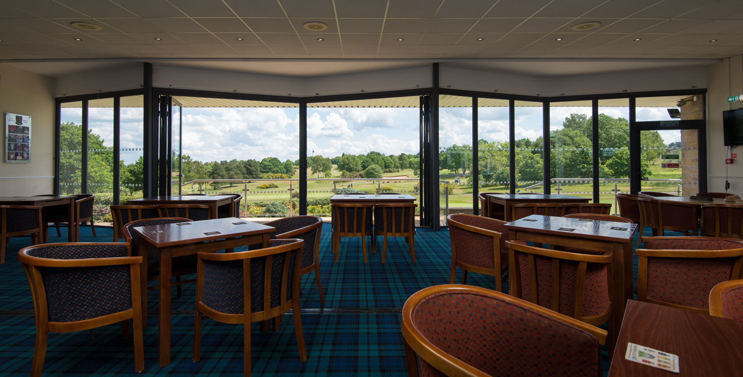 View from inside a golf club looking out through bifold doors onto the course