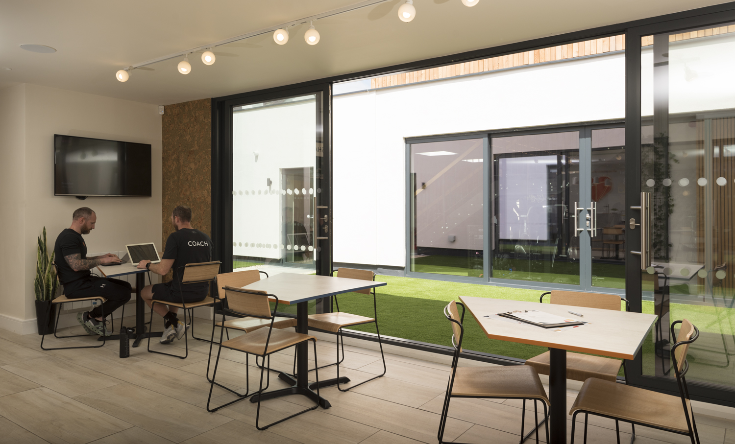 Set of open bifold doors looking into the courtyard with two men discussing work at a table