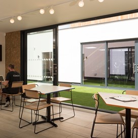 Set of open bifold doors looking into the courtyard with two men discussing work at a table