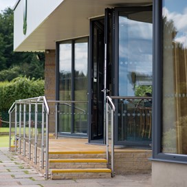 Golf club bifold doors viewed from the side with golfers in the background