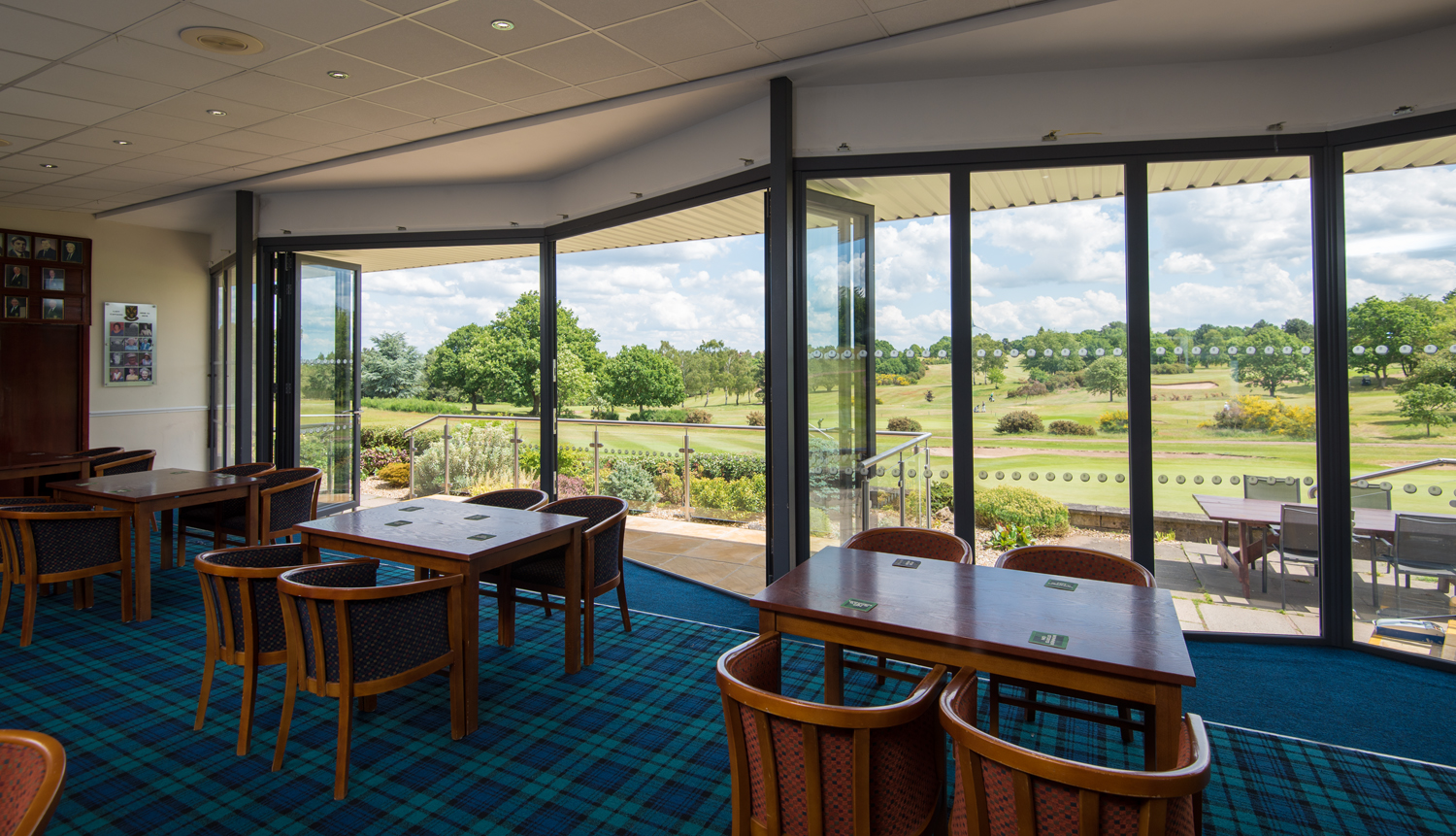 Inside of a golf club viewing the course through closed bifold doors