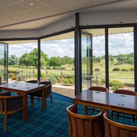 Inside of a golf club viewing the course through closed bifold doors