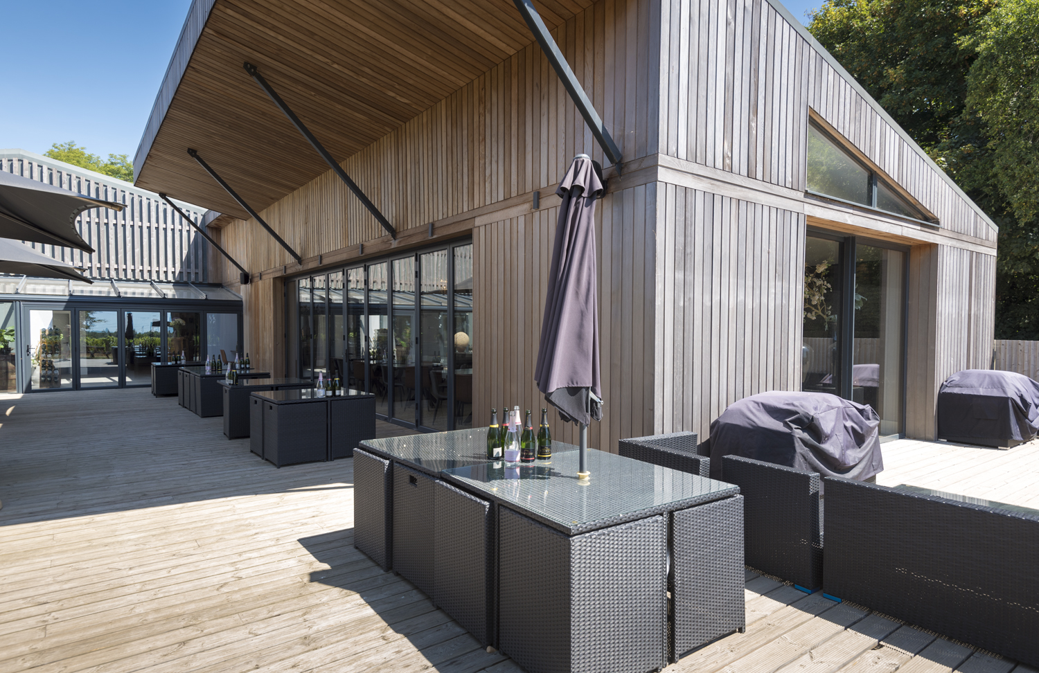 A bar garden with tables fitted with umbrellas with Origin bifolds in the background