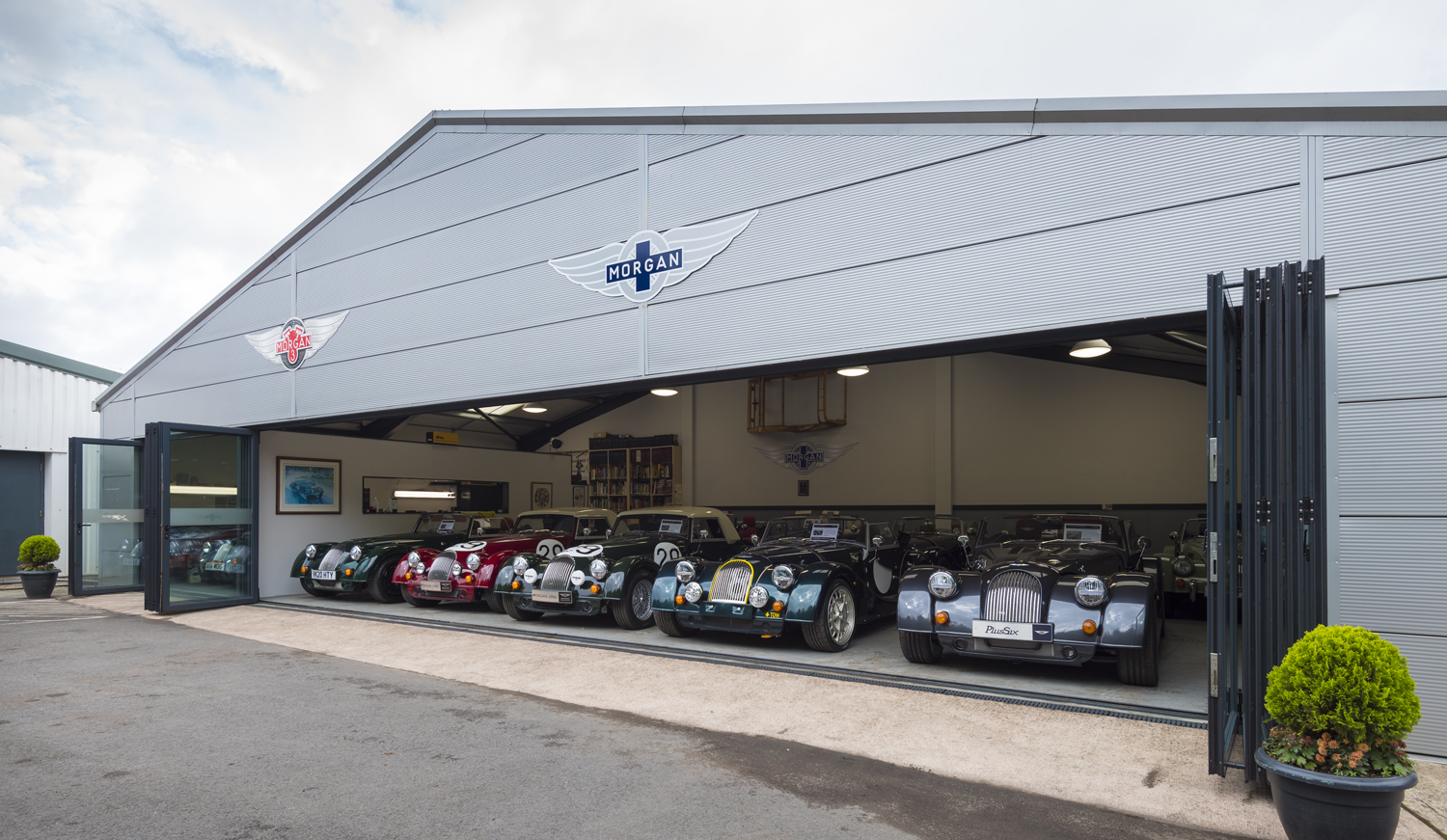 Open bifold doors looking into a car showroom with a row of cars