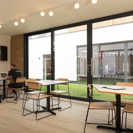 Two men sitting at a table inside a room looking through a set of Origin bifold doors