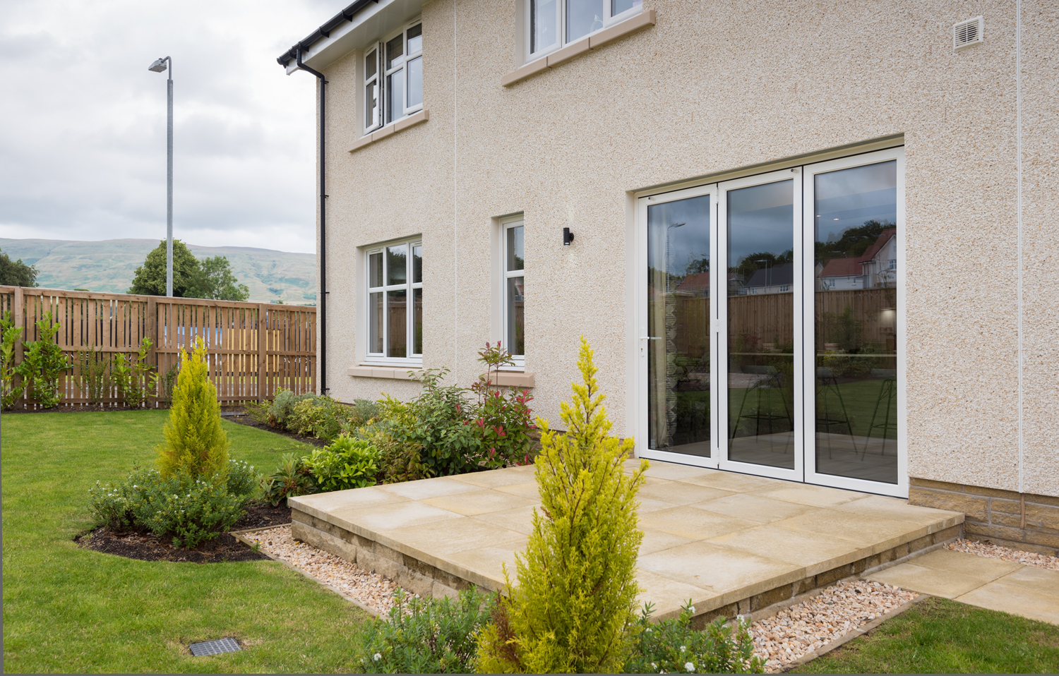 Side view of a modern house from the garden with closed white bifold doors