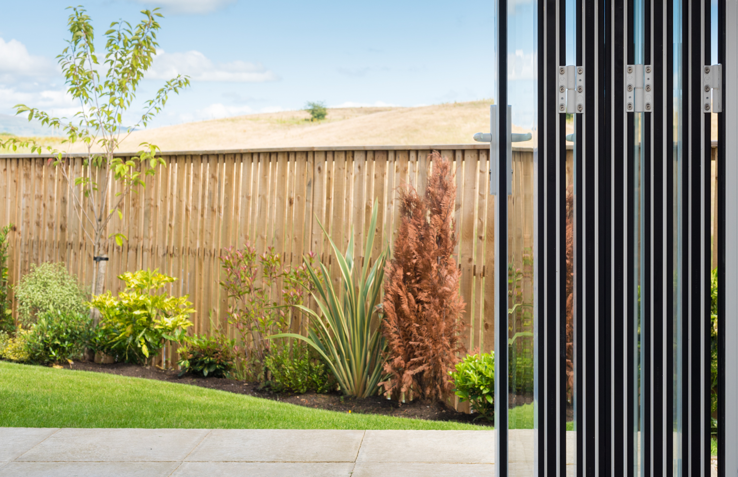 View from inside through open bifold doors leading into the garden