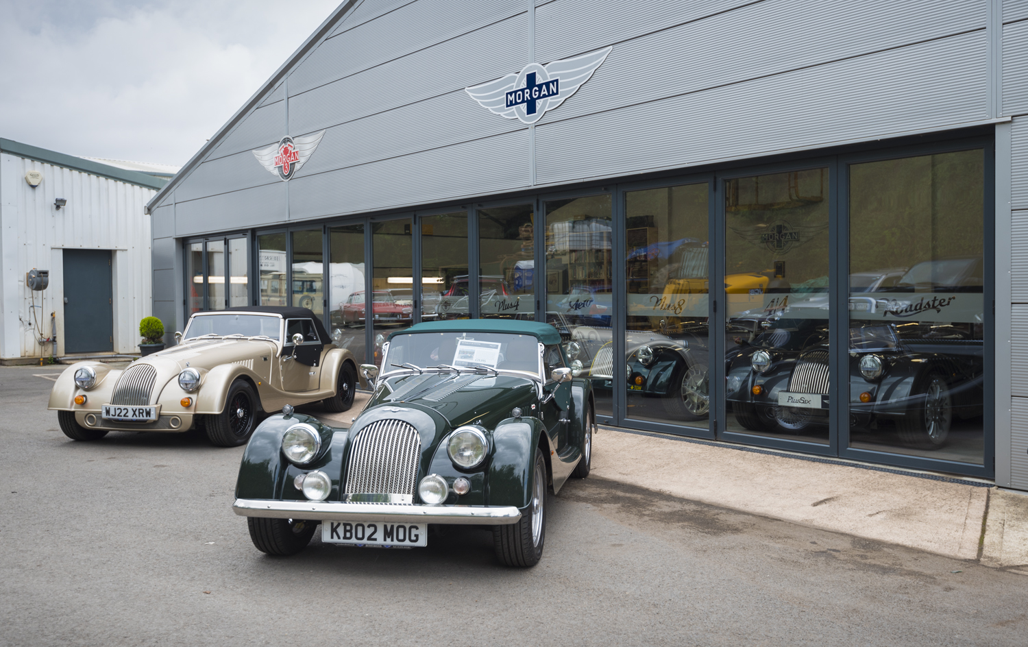 Two old cars in the front of a car showroom fitted with Origin bifold doors