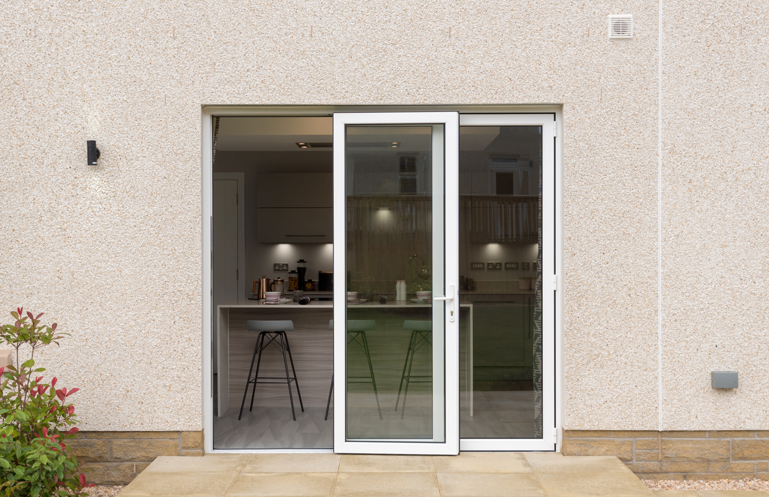 Half open white bifolds fitted into the side of a modern house