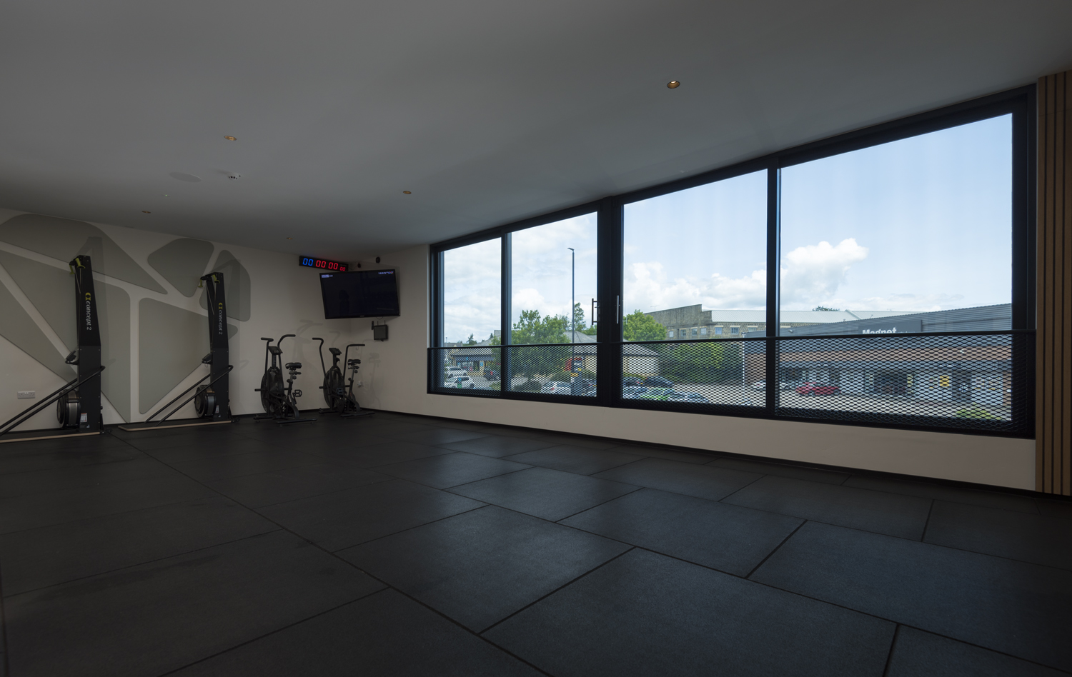 View of gym equipment within the upper floor of a gym with a view through Origin Windows