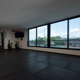 View of gym equipment within the upper floor of a gym with a view through Origin Windows